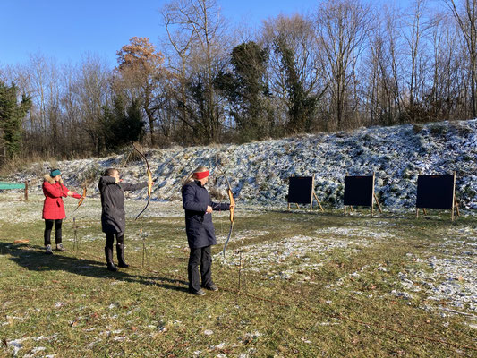 Drei Personen beim meditativen Bogenschiessen im Winter