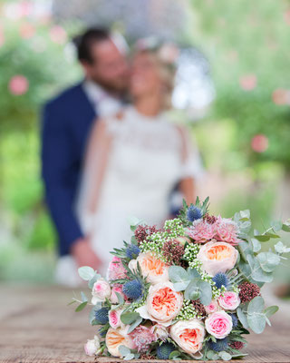 photo de couple de mariés ; derrière le bouquet de fleurs