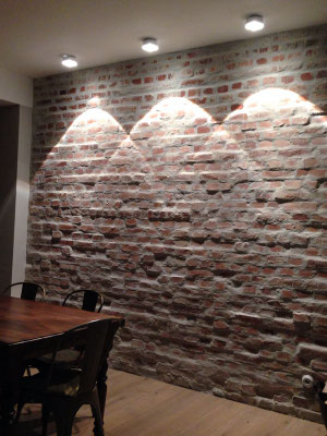 Deckeneinbauspots mit markanten Lichtkegeln setzten die Natursteinwand in Szene – Lichtplanung für ein  Einfamilienhaus in Köln