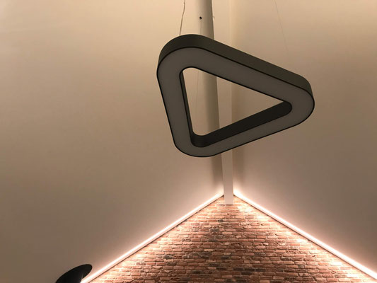 Deckenintegrierte Lichtlinien betonen die Materialität der Natursteinmauer