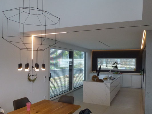 Eine wand- und deckenübergreifende Magnetschiene mit austauschbaren Lichteinheiten verlaüft lückenlos vom Ess- zum Wohnbereich