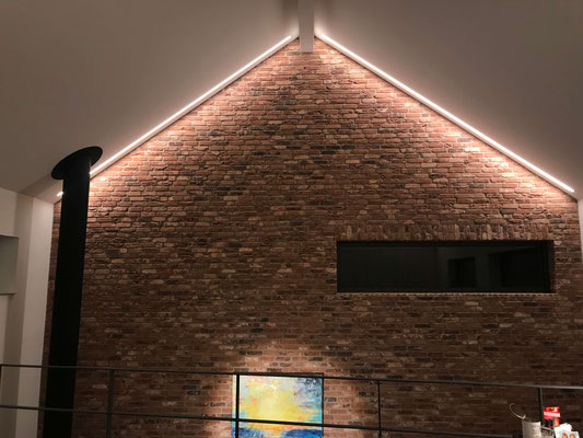 Deckenintegrierte Lichtlinien betonen die Materialität der Natursteinmauer