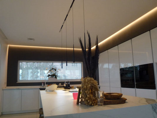 Die Beleuchtung des Küchenblocks übernehmen dekorative Pendelleuchten in Kombination mit engabstrahlenden Lichteinheiten  