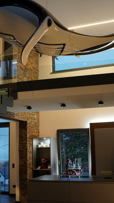 Eine deckenintegrierte Lichtlinie spendet zusammen mit einer Hinterleuchtung der Küchenmöbel Ambientelicht für Küche und Galerie