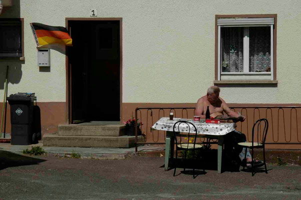 56- Deutschlandfahne vor deutschem Haus mit deutschem Zeitungsleser