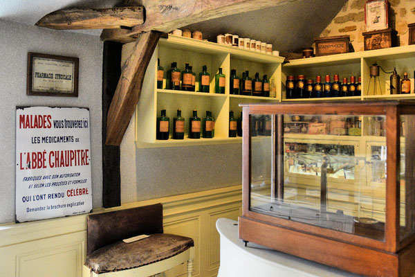 Pharmacie : l'officine de l'Apothicaire avec ses étagères garnies de pots, de bouteilles et de tout le nécessaire pour les mesures et les préparations   
