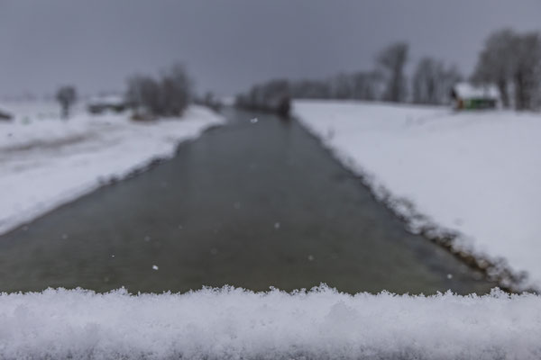 Schnee auf einer Brücke eines Flusses