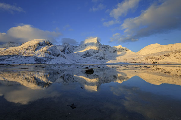 Verschneite Berge spiegeln sich in Fjord