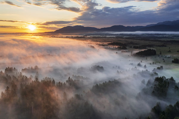 Nebel bei Sonnenaufgang vor Bergen
