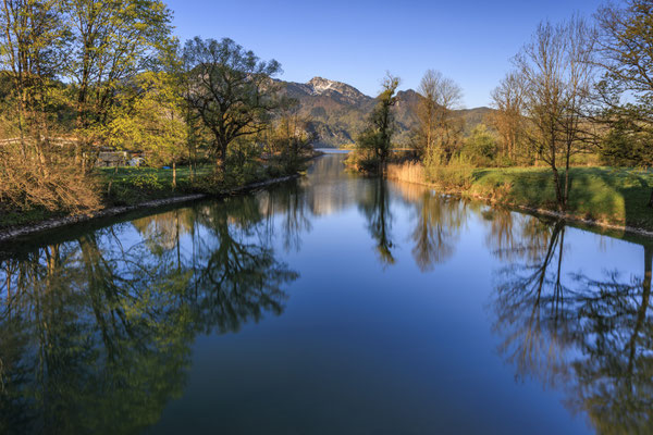 Ein Fluss vor einer Berglanschaft im Frühling bei Morgenlicht