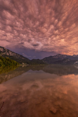 Gewitterwolken spiegeln sich in einem Bergsee
