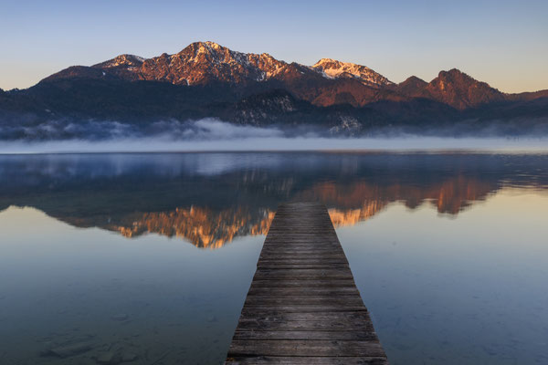 Berge spiegeln sich bei Sonnenaufgang in einem See