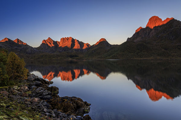 Berge spiegeln sich bei Sonnenaufgang in Fjord