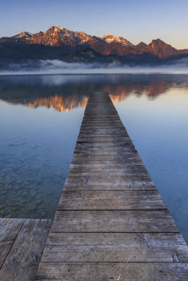 Berge spiegeln sich bei Sonnenaufgang in einem See