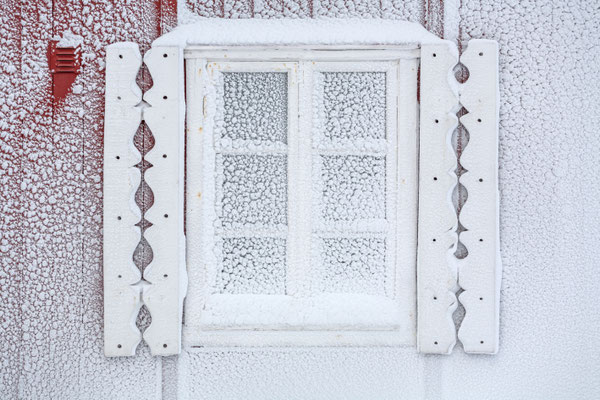 Verschneites Fenster an rotem Haus