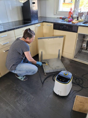 Petra Kohler beim Reinigen der Küchenschränke mit Dampfgerät 