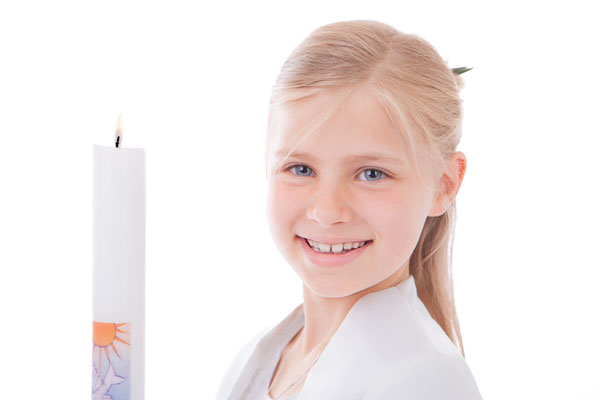 Dieses Bild zeigt eine Studioaufnahme eines  blonden Mädchens im Kommunionkleid mit brennender Kerze vor weißem Hintergrund als Kopfporträt