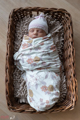 Dies ist eine Newbornaufnahme eines Babys im Boho-Look im Weidenkorb und gepuckt