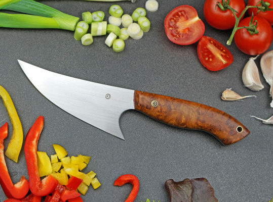 Ein Kräutermesser aus fein ausgeschliffenem Kugellagerstahl mit einer schützenden Fingermulde. Griffmaterial: stabilisiertes Thuja-Maserholz