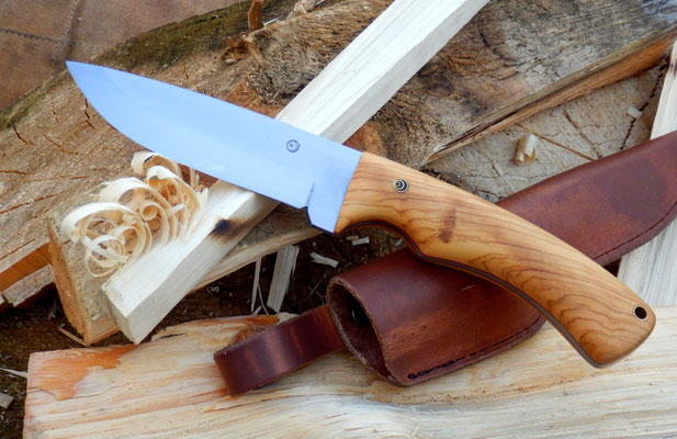 Ein Outdoor Messer aus Kohlenstoffstahl, mit einem Griff aus wildem Olivenholz und einer heißgewachsten Lederscheide.