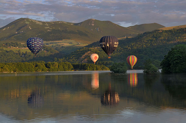 vier Heißluftballons in Murol Frankreich Spiegelung im See