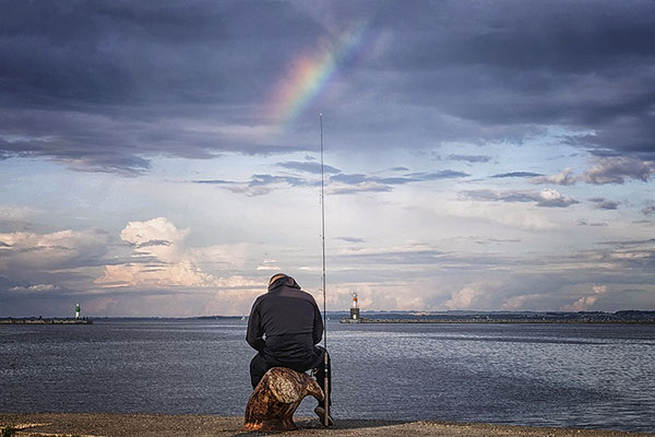 Angler am Ufer mit Regenbogen