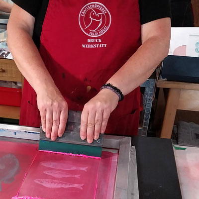 Eine Teilnehmerin druckt einen Siebdruck auf Papier im Workshop.