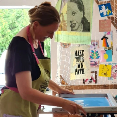 Frau mit einem Siebdrucksieb in der offenen Werkstatt für künstlerische Druckgrafik in Niedersachsen.