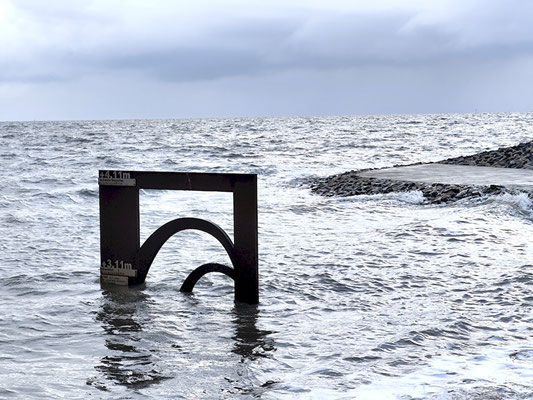 Das Sturmflutmahl an der Perlebucht in Büsum spiegelt sich im durch eine Sturmflut aufgewühltem Wasser