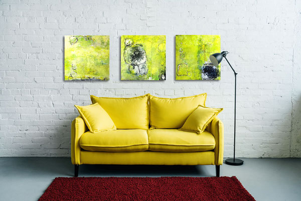 Wandgestaltung mit einer Bilderserie in unterschiedlicher Hängung mit gelbem Sofa