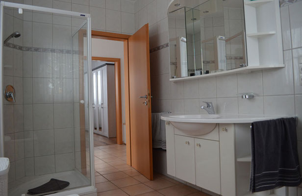 Helles, gepflegtes Badezimmer der FeWo Olli mit weißer Keramik, großem Waschtisch und Dusche mit flachem Einstieg.