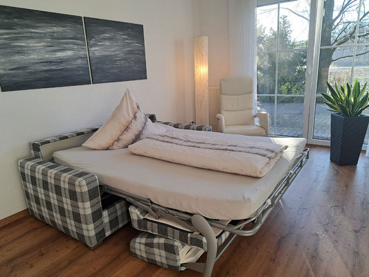 Wohnzimmer der Ferienwohnung Olli mit zum Doppelbett (150x200 cm) ausgezogener Schlafcouch.