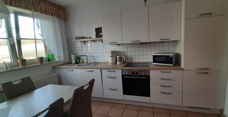 Voll ausgestattete Einbauküche mit Mikrowelle, Kaffeemaschine, Wasserkocher, Spülmaschine, Backofen, Kühlschrank mit 3-Sterne-Gefrierfach sowie Esstisch mit 4 Stühlen.
