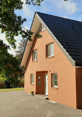 Giebelansicht der Ferienwohnung Olli mit Eingangsbereich und großzügiger Hoffläche als hauseigener Parkplatz direkt vor der Tür.