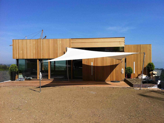 weisses Sonnensegel vor modernem Holzhaus