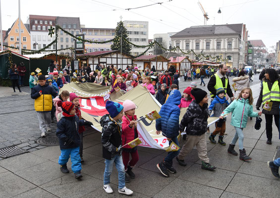 Mit einem Friedensmarsch und den formulierten Friedenswünschen geht es für die rund 500 Schulkinder Richtung Augsburger Rathaus. © Theresa Meier