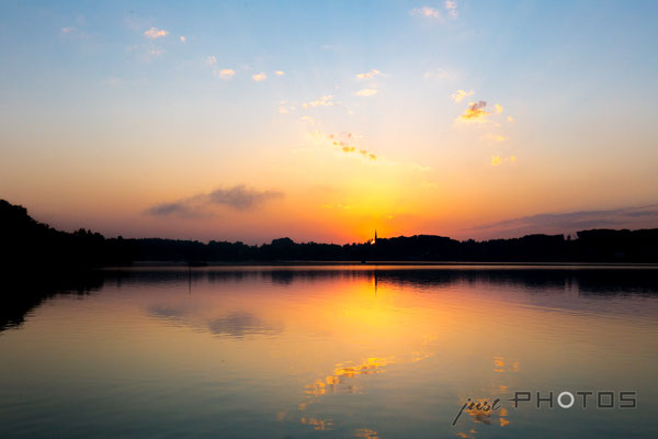 Sonnenaufgang am Wörthsee - die Sonne erscheint unmittelbar hinter dem Kirchturm von Steinebach