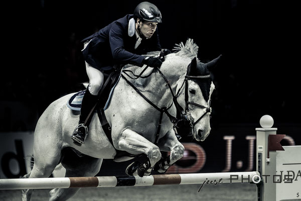 Munich Indoors - Springreiten - Pferd mit Reiter beim Sprung über ein Hindernis (Schwarz-Weiß)