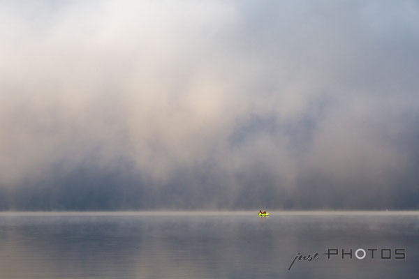 Dichter Nebel lichtet sich über dem Wörtsee, von der Sonne angestrahlt ein Fischerboot