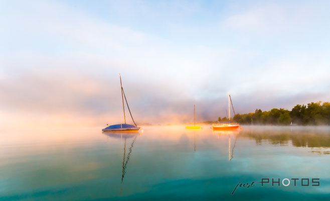 Segelboote im Wörthsee bei Nebel im Licht der aufgehenden Sonne