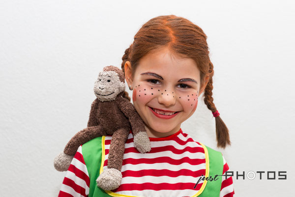 Mädchen - mit roten Zöpfen und geschminkt als Pippi Langstrumpf mit Stoff-Affe „Herr Nilsson“ auf der Schulter