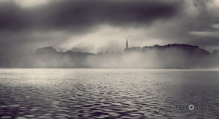 Sonnenaufgang mit Nebel am Wörthsee - im Hintergrund die Kirche von Steinebach (Schwarzweiss)
