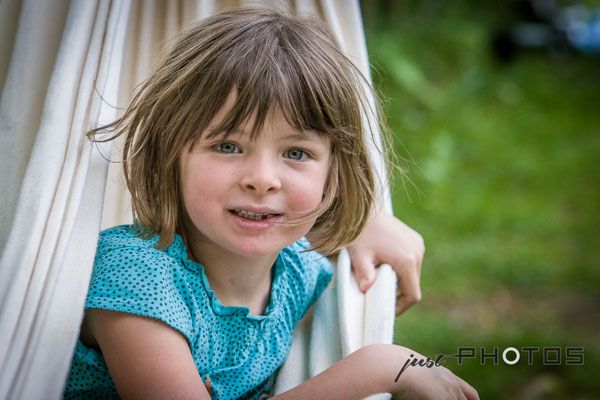 Mädchen sitzt in Hängematte und schaut heraus