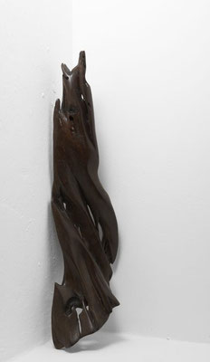 Abstract tropical driftwood sculpture S1100 by Jörg Pietschmann, featuring a dynamic, slender wing-like shape made of dark brown polished wood with deep organic grooves, natural elongated perforations, and weathered textures against a white studio wall.