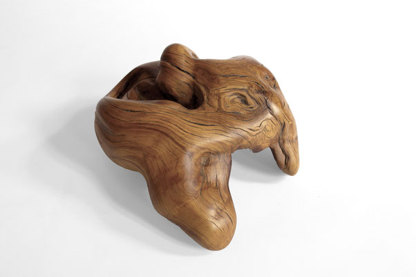 horizontal biomorphic oak wood sculpture by Jörg Pietschmann, showcasing fluid organic folds and golden-brown grain on a white background.