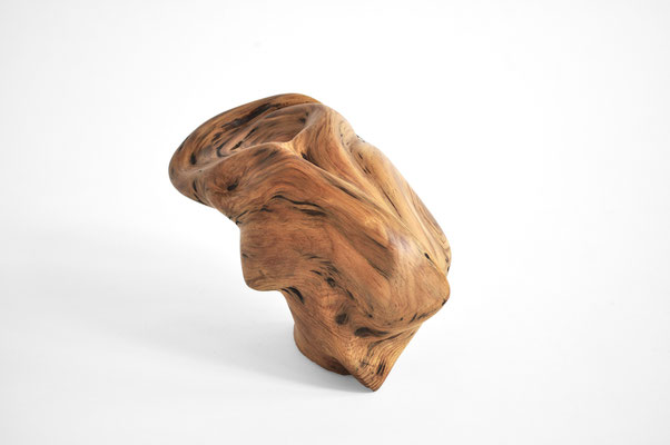 Abstract Aleppo pine wood sculpture S1369 by Jörg Pietschmann, showing a polished, golden-brown organic form with fluid, swirling grain patterns, wave-like dynamic lines, and dark natural accents on a solid white studio background.