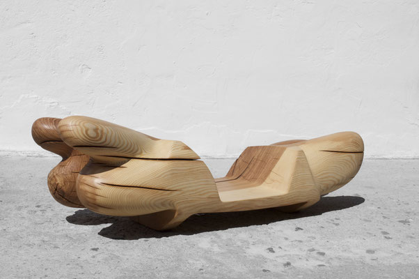 undulating oak wood sculpture V1558 by Jörg Pietschmann, showcasing its smooth grain and dynamic organic curves, shot on concrete against a white wall.