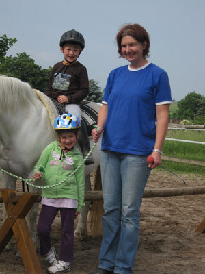 Reitlehrerin mit Kindern und einem weißen Pony