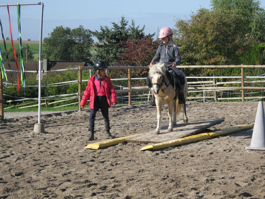 Ein Mädchen ist mit dem Pony Speedy auf die Wippe geritten und kann mit ihm Gewichtsverlagerung üben.