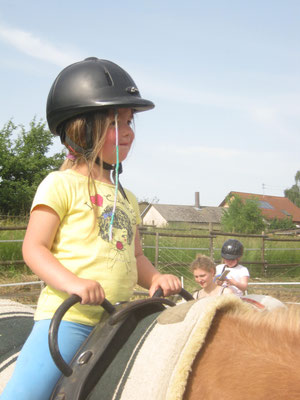 Ein Mädchen reitet sehr glücklich auf dem Pony.